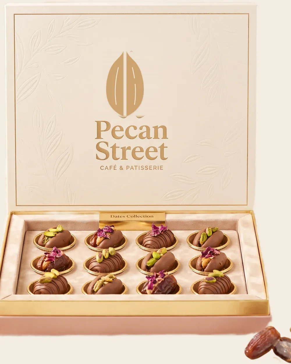 Open presentation box of stuffed dates in a fitted tray, lid showing the foiled wordmark